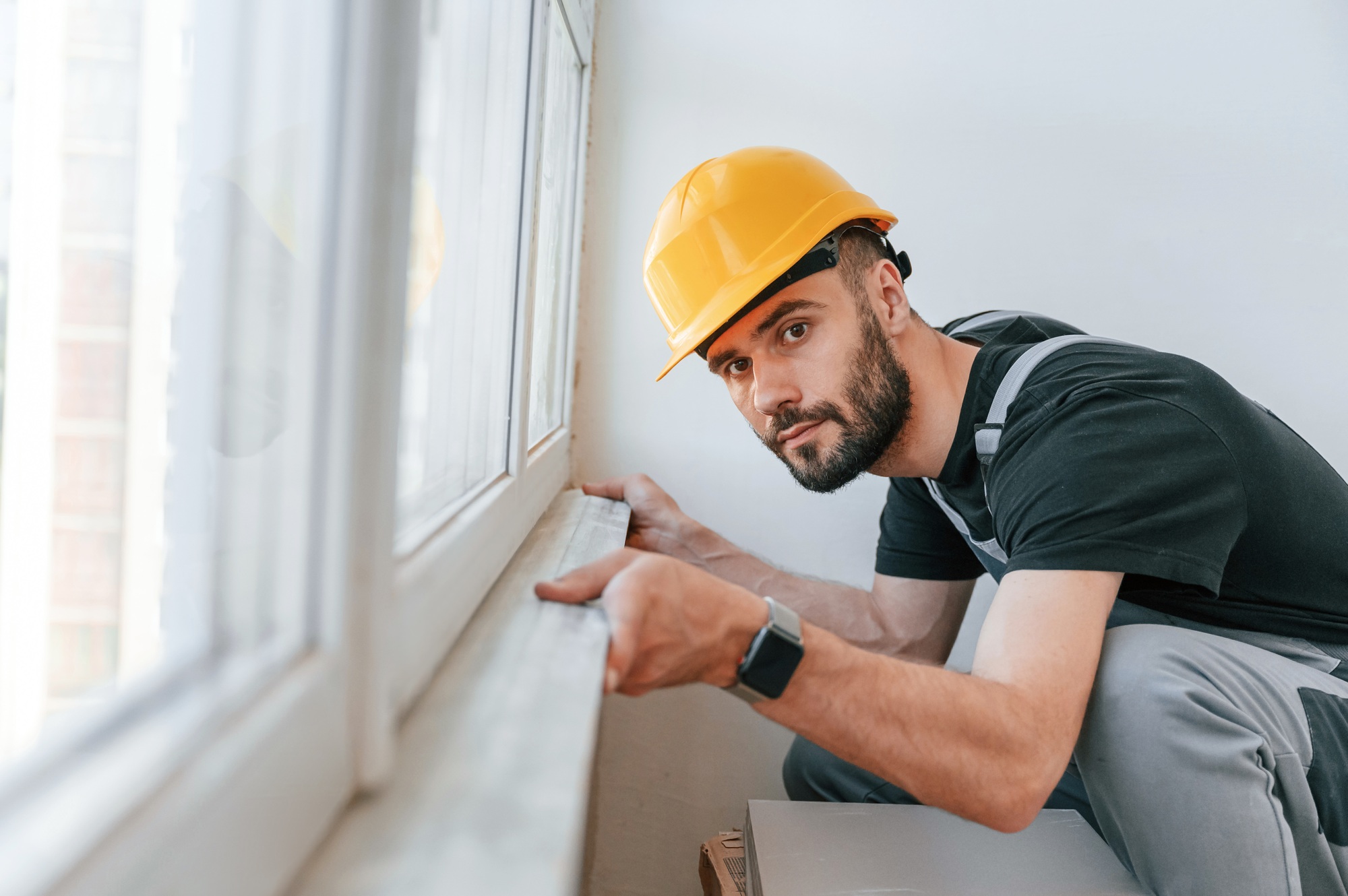 Installing a window sill. The man is making repairs in the apartment