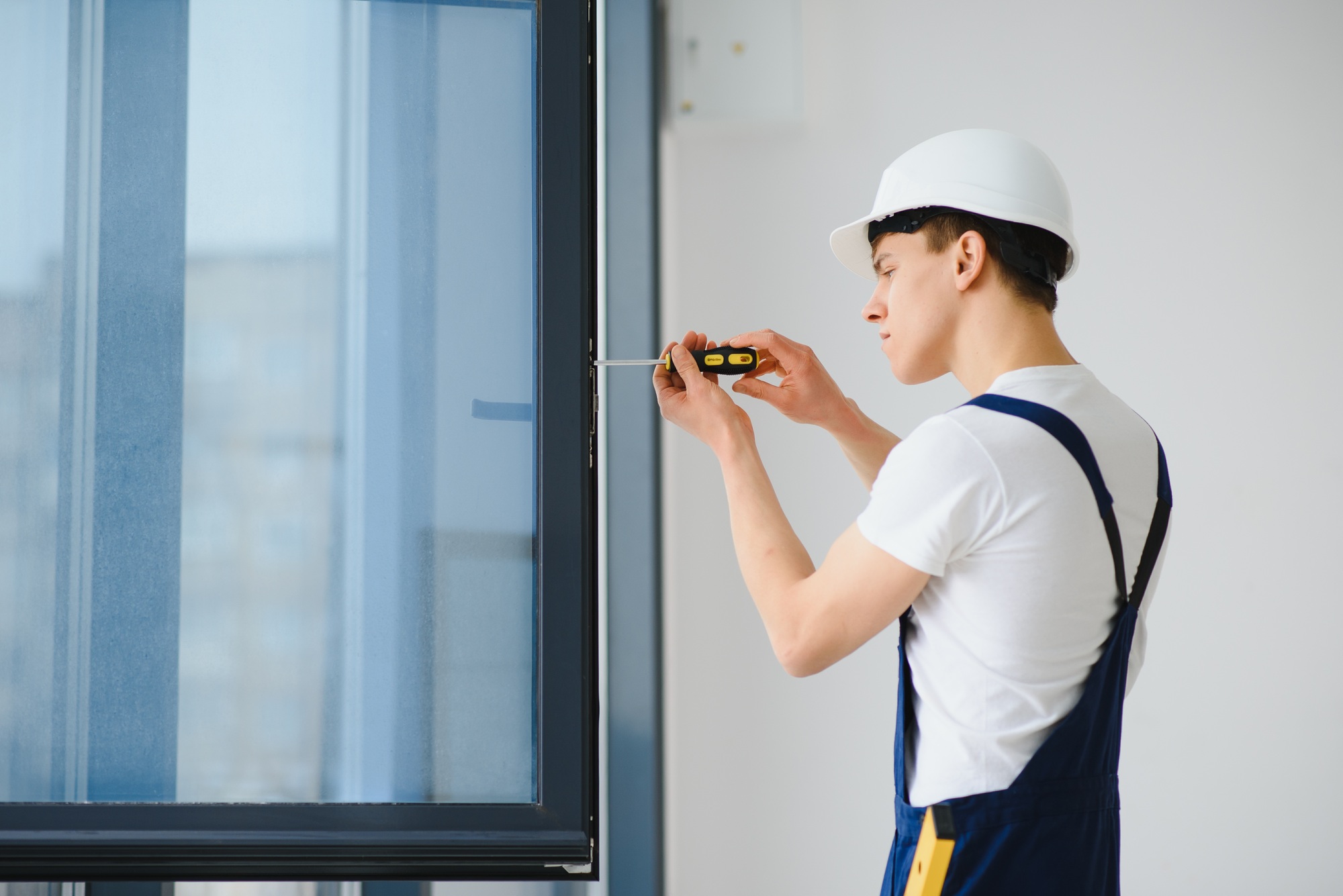 Young handyman repair window with screwdriver